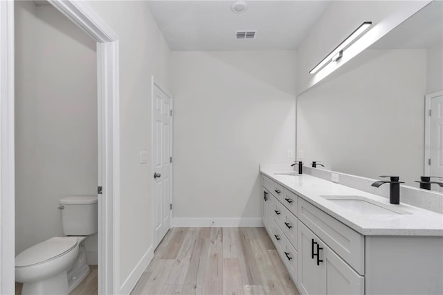 bathroom with a sink, visible vents, toilet, and wood finished floors