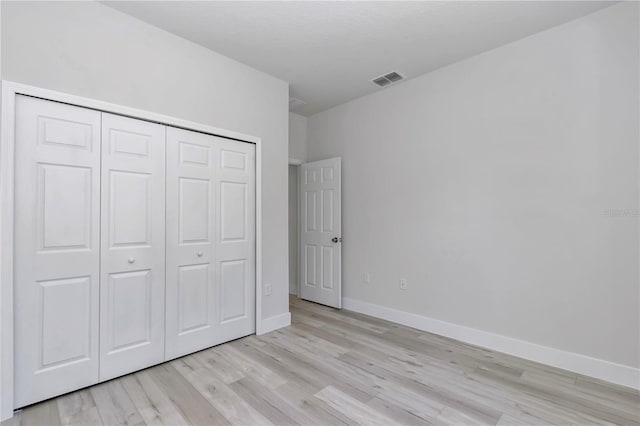 unfurnished bedroom featuring a closet, baseboards, light wood-style floors, and visible vents