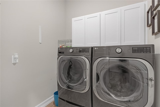 clothes washing area with washer and dryer, baseboards, and cabinet space