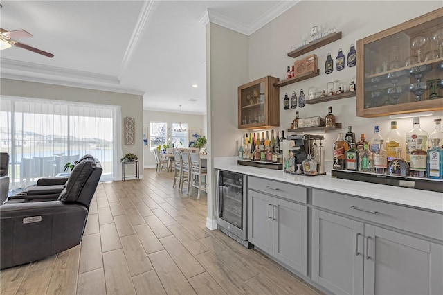 bar with beverage cooler, wood finish floors, ceiling fan, crown molding, and a dry bar