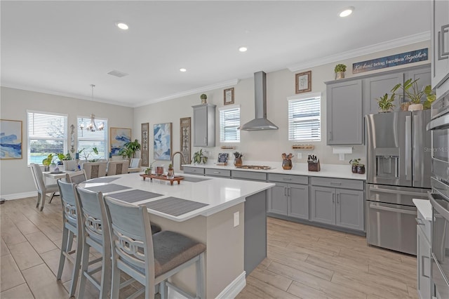 kitchen featuring gray cabinets, appliances with stainless steel finishes, wall chimney exhaust hood, and a sink