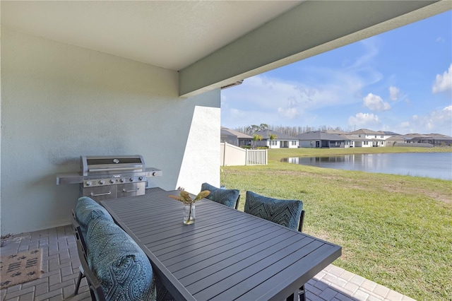 view of patio featuring a water view, outdoor dining space, fence, a residential view, and a grill