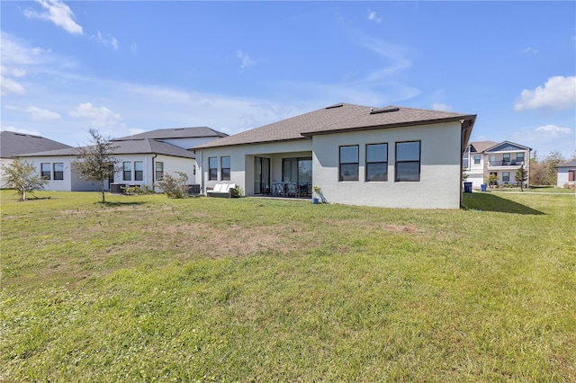 rear view of house with a yard and stucco siding