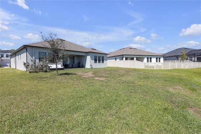 rear view of property with fence, a lawn, and stucco siding