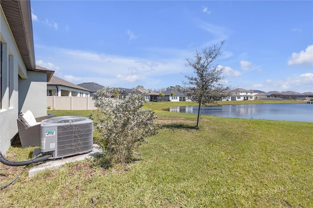 view of yard with a residential view, a water view, central AC, and fence