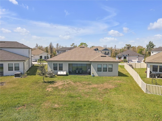 rear view of house featuring cooling unit, a fenced backyard, stucco siding, a lawn, and a residential view