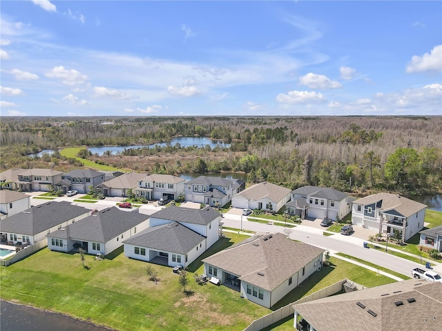 drone / aerial view featuring a residential view, a view of trees, and a water view