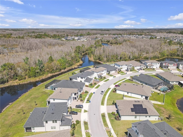 drone / aerial view featuring a wooded view, a water view, and a residential view