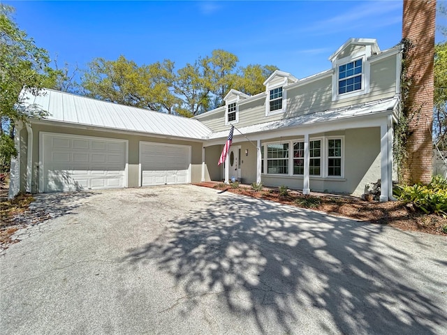 view of front facade featuring aphalt driveway, stucco siding, metal roof, a garage, and a standing seam roof