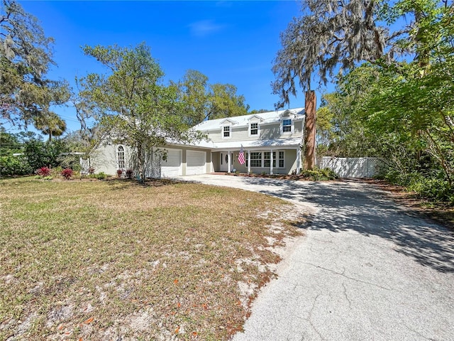 view of front of house featuring a front yard, fence, driveway, an attached garage, and a chimney