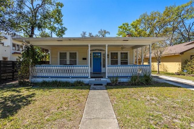 bungalow-style home featuring a front lawn, fence, and covered porch