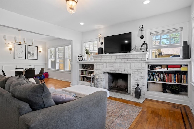 living area with wood finished floors, a brick fireplace, recessed lighting, and a healthy amount of sunlight