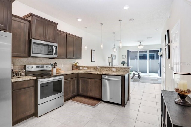 kitchen with a sink, dark brown cabinetry, appliances with stainless steel finishes, a peninsula, and decorative backsplash