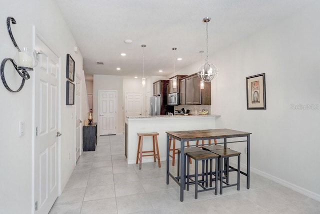 kitchen featuring baseboards, a peninsula, recessed lighting, stainless steel appliances, and decorative light fixtures