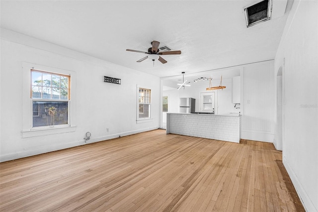 unfurnished living room featuring light wood-style flooring, baseboards, visible vents, and ceiling fan