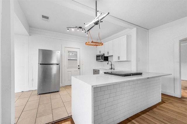 kitchen featuring visible vents, light countertops, stainless steel appliances, white cabinetry, and a sink