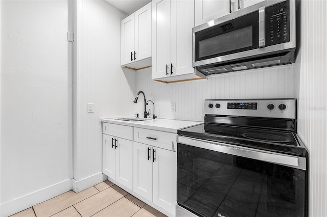 kitchen with appliances with stainless steel finishes, white cabinetry, light countertops, and a sink