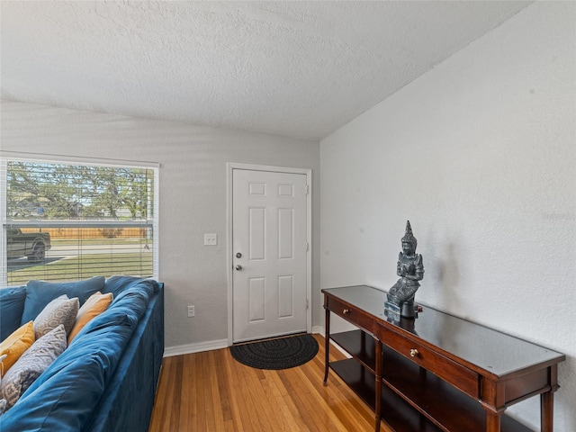 entrance foyer with a textured ceiling, baseboards, and wood finished floors