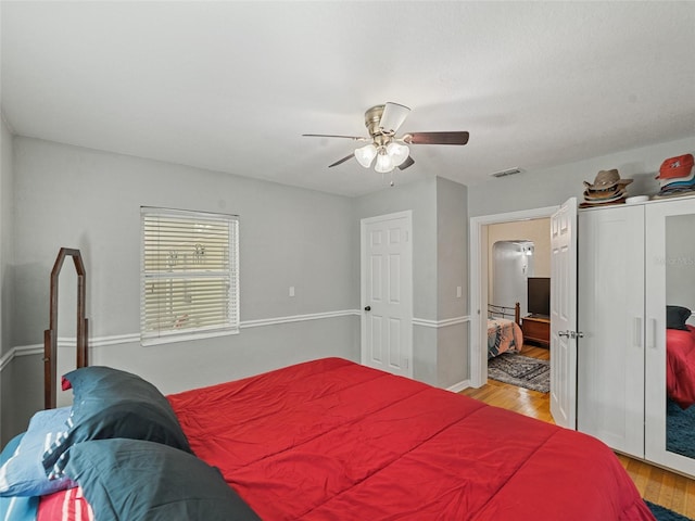 bedroom featuring light wood-style flooring, visible vents, and ceiling fan