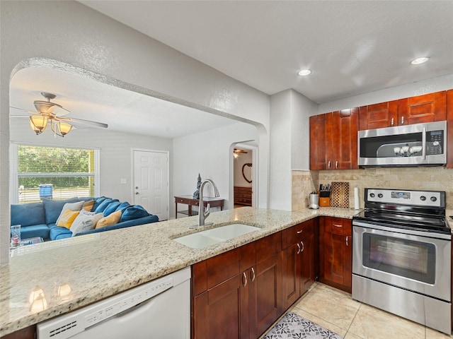 kitchen with a sink, backsplash, stainless steel appliances, arched walkways, and light tile patterned floors