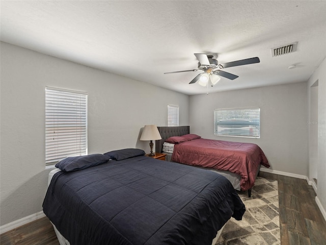 bedroom with visible vents, baseboards, a ceiling fan, and dark wood-style flooring