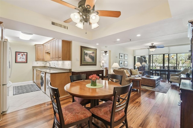 dining area with visible vents, washer / clothes dryer, light wood-style floors, and ceiling fan