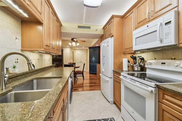 kitchen with visible vents, light tile patterned floors, decorative backsplash, white appliances, and a sink