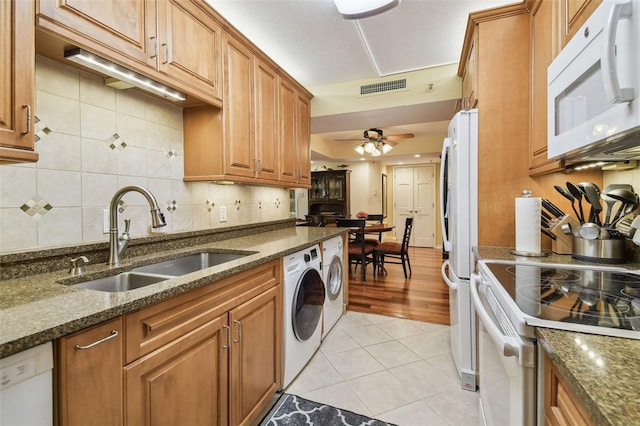 kitchen featuring visible vents, a sink, white appliances, brown cabinetry, and light tile patterned floors