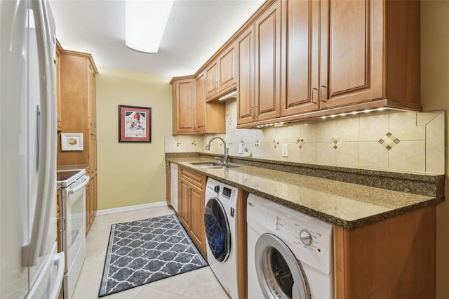 laundry area featuring a sink, baseboards, light tile patterned flooring, and washing machine and clothes dryer