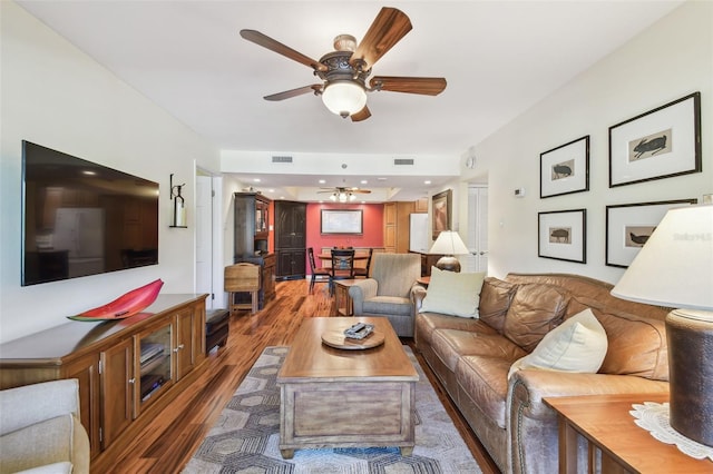 living area featuring wood finished floors, a ceiling fan, and visible vents