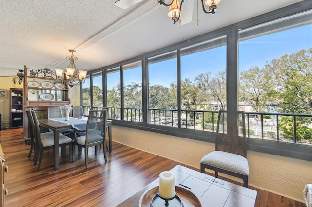 dining area featuring a chandelier, a textured ceiling, a textured wall, and wood finished floors