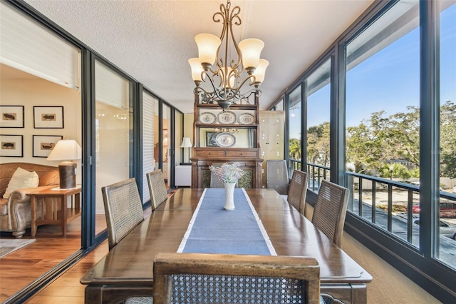 dining room featuring expansive windows, a notable chandelier, wood finished floors, and a textured ceiling