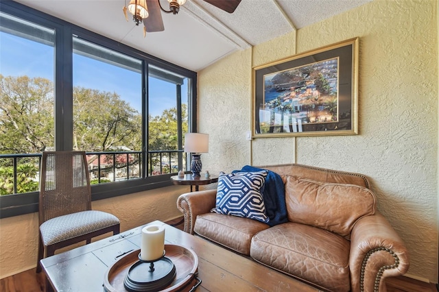 living area featuring ceiling fan and a textured wall