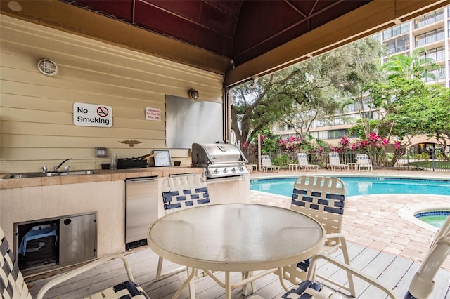 exterior space featuring outdoor dining space, area for grilling, a community pool, and a sink