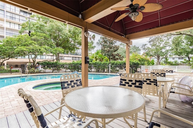 pool featuring outdoor dining area, a community hot tub, a ceiling fan, and fence