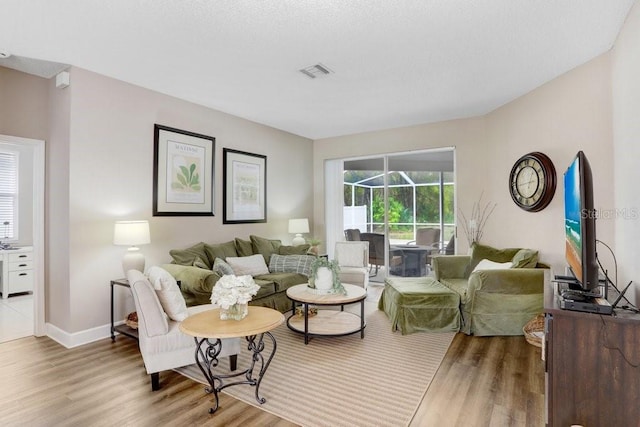 living room featuring wood finished floors, visible vents, and baseboards