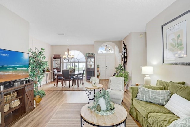 living area with a chandelier, visible vents, and light wood finished floors