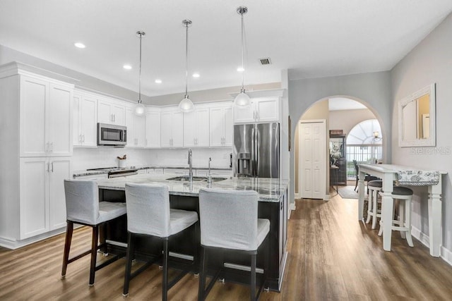 kitchen featuring visible vents, arched walkways, a sink, white cabinets, and appliances with stainless steel finishes