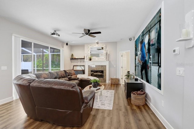 living room featuring wood finished floors, visible vents, baseboards, a fireplace, and ceiling fan