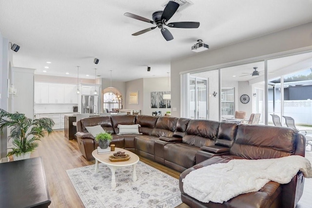 living room featuring light wood-style flooring, recessed lighting, a ceiling fan, and a wealth of natural light