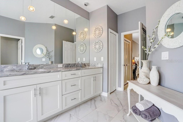 full bath with visible vents, double vanity, a sink, marble finish floor, and connected bathroom