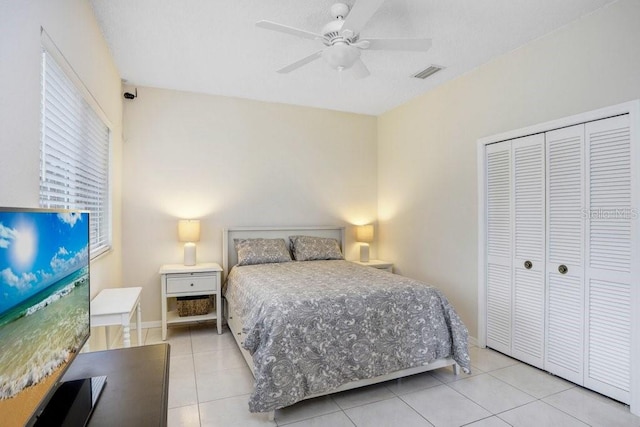 bedroom with baseboards, visible vents, light tile patterned flooring, ceiling fan, and a closet