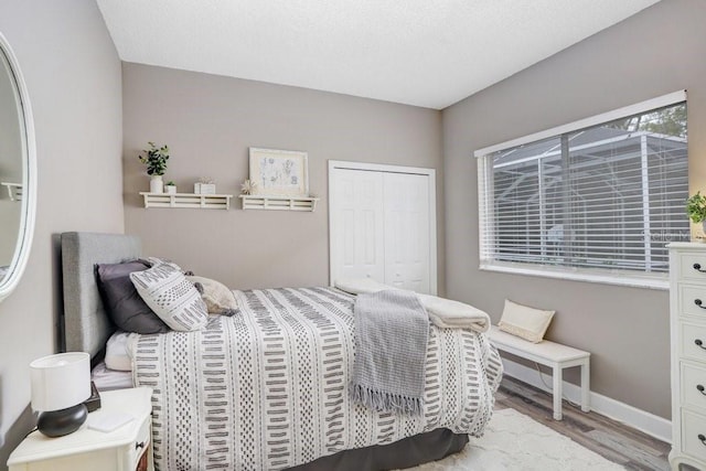 bedroom featuring wood finished floors, a closet, and baseboards