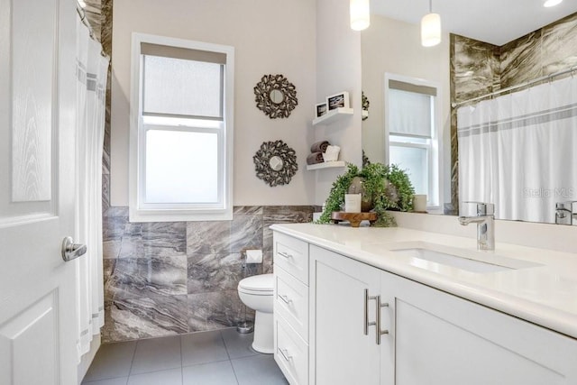 bathroom with vanity, tile patterned flooring, wainscoting, tile walls, and toilet