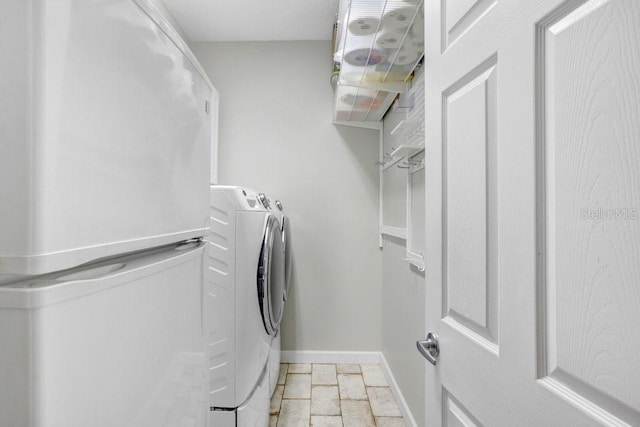 clothes washing area with stone finish floor, laundry area, washer and dryer, and baseboards