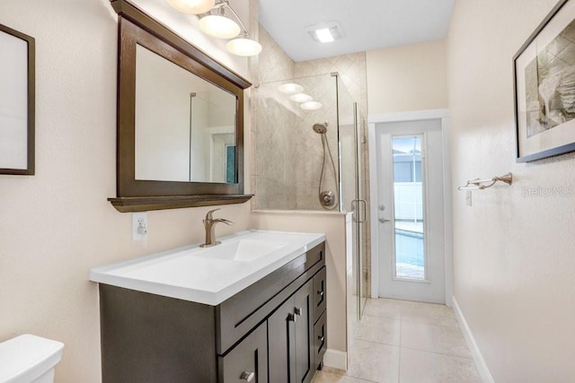 bathroom featuring tile patterned floors, toilet, a stall shower, baseboards, and vanity