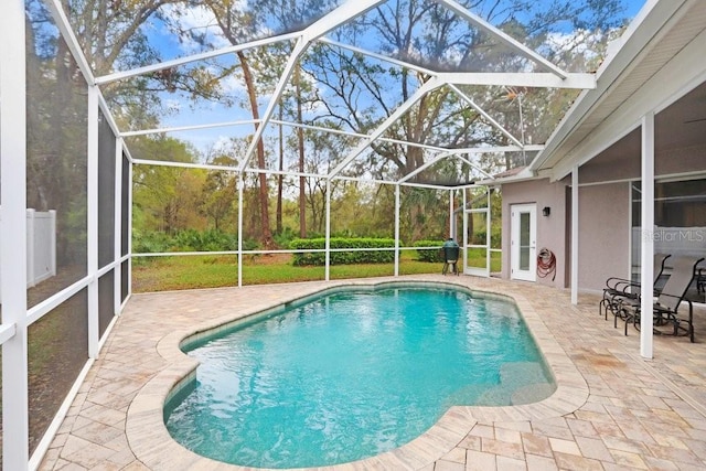 outdoor pool featuring glass enclosure and a patio area