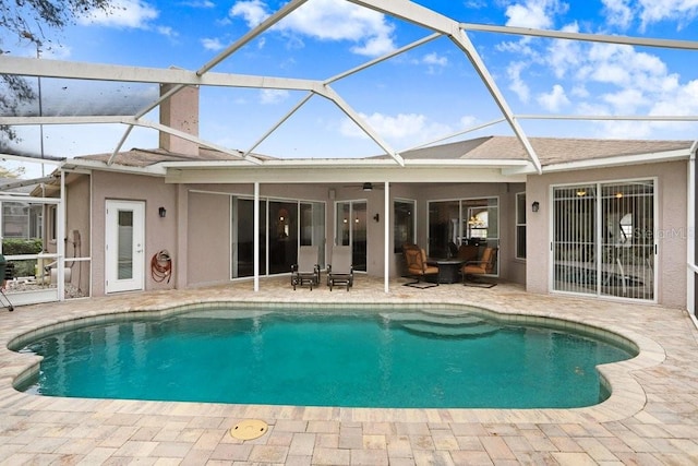 outdoor pool with glass enclosure, ceiling fan, and a patio area