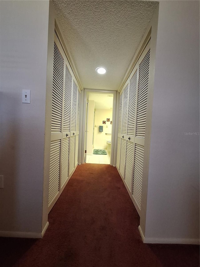 hall featuring carpet flooring, a textured ceiling, and baseboards