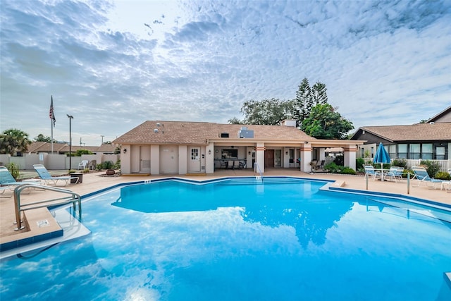 community pool with a patio area and fence